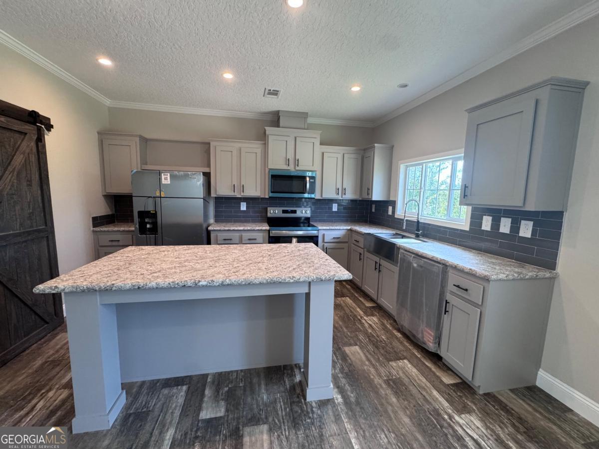 44 Long Leaf Road Hazlehurst, GA 31539 - Photo 20 of 21 a kitchen with stainless steel appliances granite countertop a sink stove refrigerator and cabinets