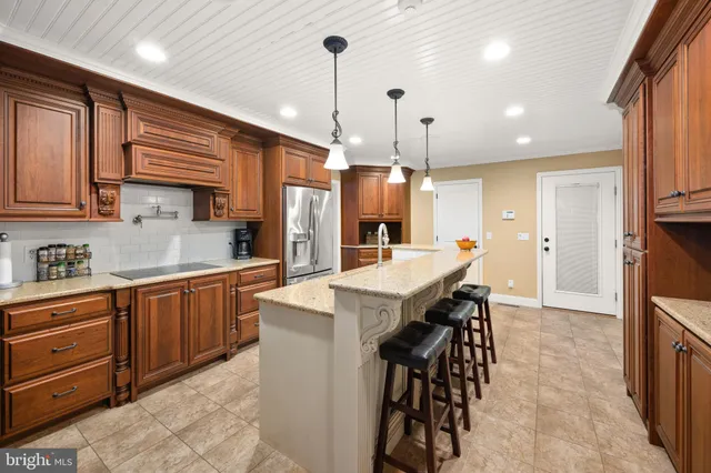 a kitchen with stainless steel appliances kitchen island granite countertop a refrigerator a sink and wooden cabinets