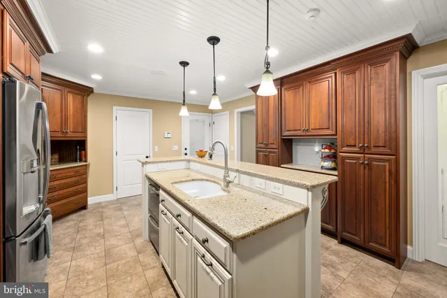 a kitchen with kitchen island granite countertop a sink a counter space appliances and cabinets
