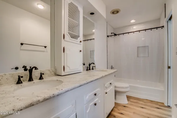 a bathroom with a granite countertop sink a toilet a mirror and shower