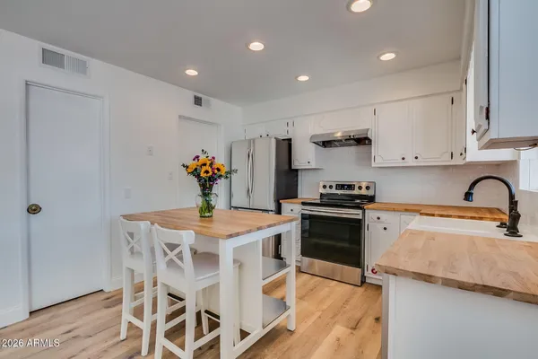 a kitchen with stainless steel appliances granite countertop a stove top oven a sink dishwasher and white cabinets with wooden floor