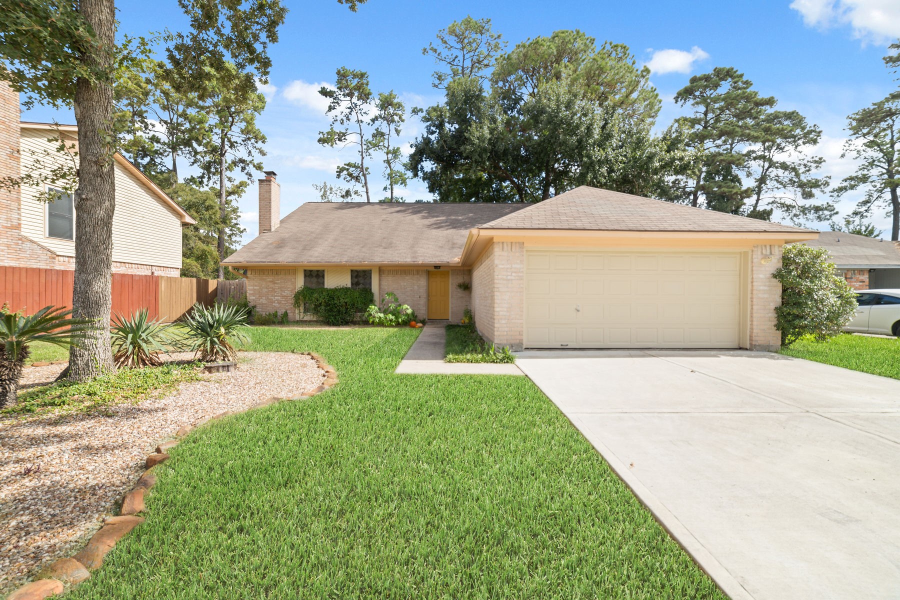 25402 Mill Pond Lane Spring, TX 77373 - Photo 4 of 24 This photo showcases a two-story brick home with a two-car garage. The well-maintained front yard features lush grass and a landscaped garden with mulch and decorative plants. The home is situated in a neighborhood with mature trees.