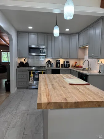a kitchen with stainless steel appliances granite countertop a sink a stove and a cabinets