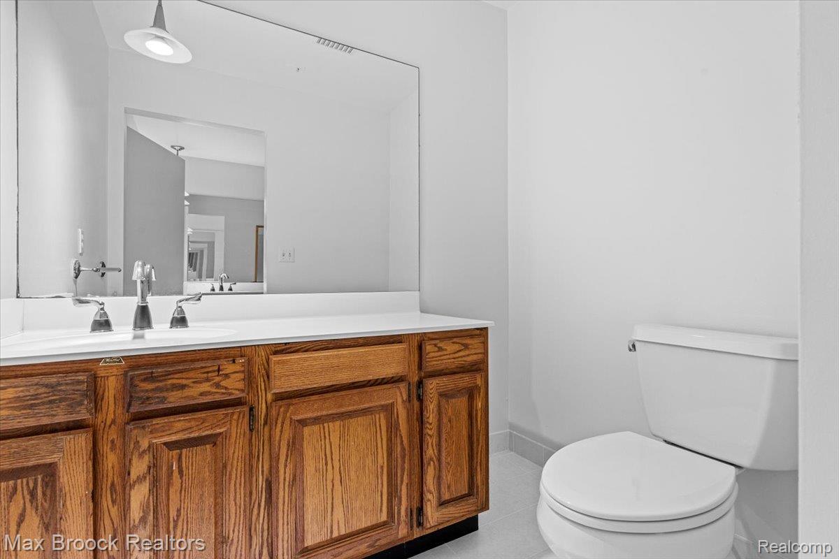 1830 Lone Pine Road Bloomfield Hills, MI 48302 - Photo 38 of 70 Bathroom featuring a wood-finish vanity with a white countertop, and a large wall-mounted mirror