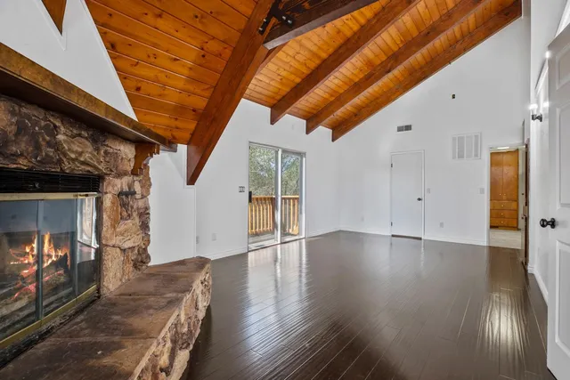 a view of an empty room with wooden floor and a fireplace
