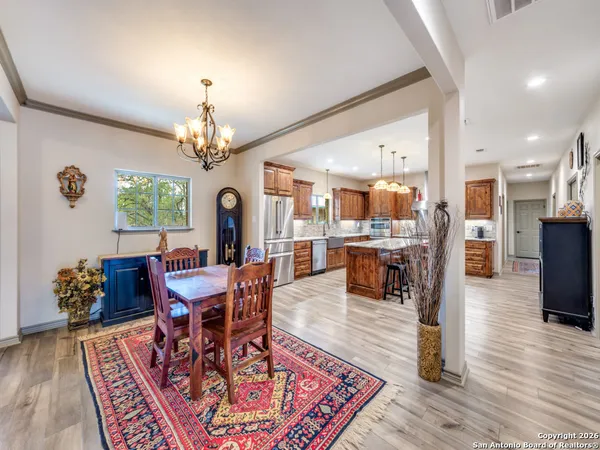 a dining room with wooden floor a chandelier a wooden table and chairs