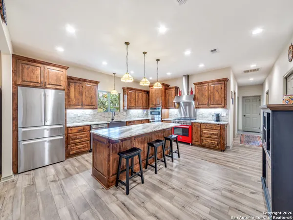 a kitchen with stainless steel appliances granite countertop a kitchen island hardwood floor sink and wooden cabinets