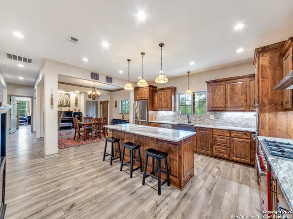 a kitchen with granite countertop a table chairs stainless steel appliances and wooden floor