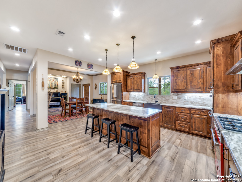 6472 Bluntzer Road Jourdanton, TX 78026 - Photo 8 of 45 a kitchen with granite countertop a table chairs stainless steel appliances and wooden floor