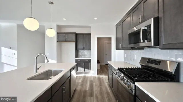 a kitchen with stainless steel appliances a stove a sink a refrigerator microwave and cabinets