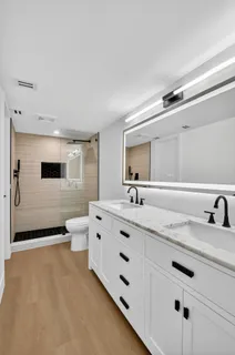 a spacious bathroom with a double vanity sink a mirror and a toilet