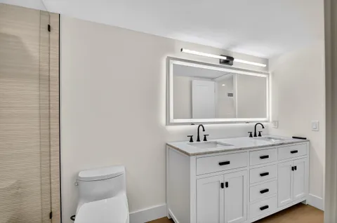 a bathroom with a double vanity sink toilet and mirror