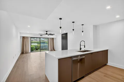 a hall with kitchen island a sink wooden floor and a large window