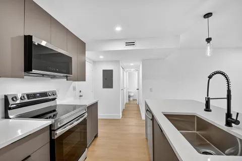 a kitchen with a sink and a stove top oven with wooden floor