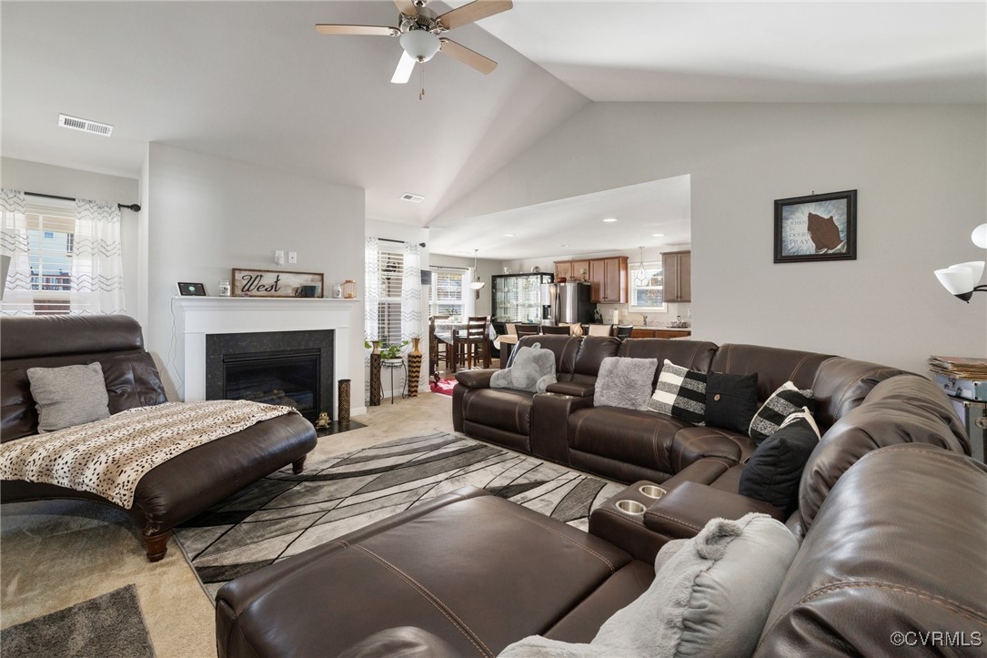 Carpeted living room featuring ceiling fan and lof
