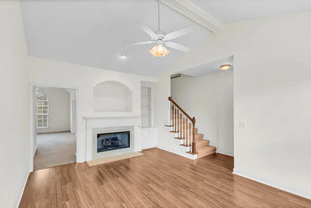 a view of an empty room with wooden floor fireplace and a window