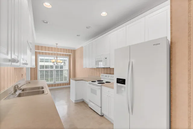 a kitchen with stainless steel appliances a refrigerator a sink a stove and white cabinets