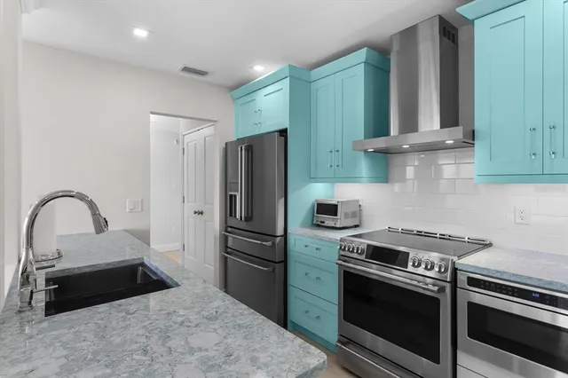 a kitchen with granite countertop a stainless steel stove and refrigerator