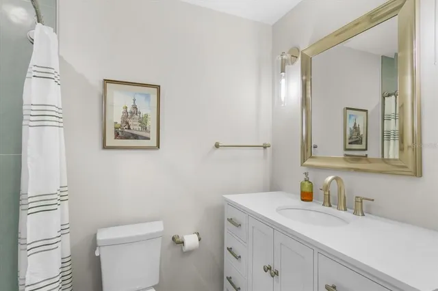 a bathroom with a granite countertop sink mirror vanity and toilet