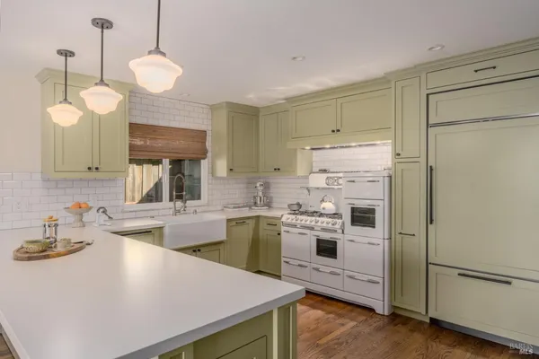a kitchen with a sink a stove a refrigerator and white cabinets