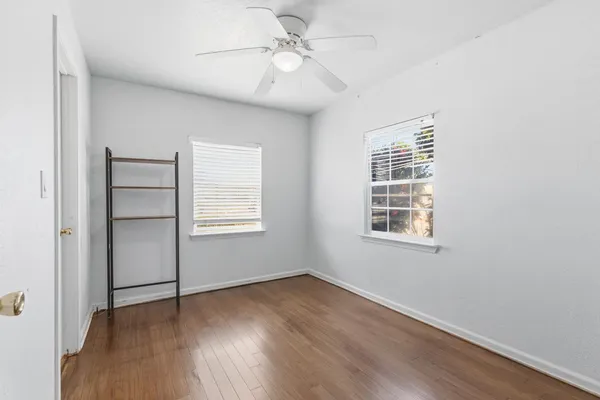 a view of an empty room with a window and wooden floor
