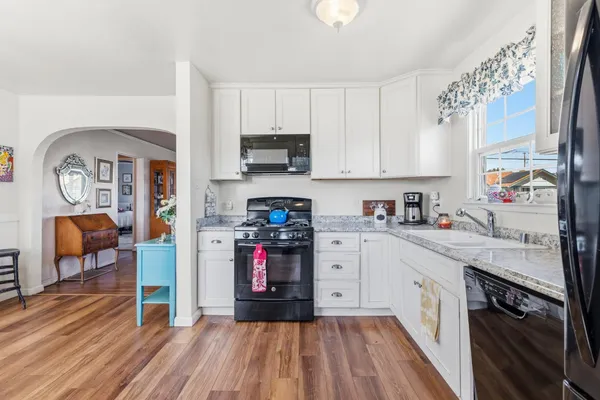 a kitchen with stainless steel appliances granite countertop a stove a sink dishwasher and a refrigerator with wooden floor