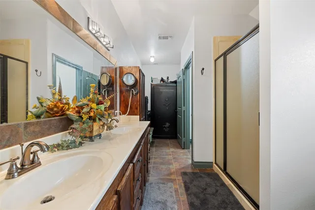 a bathroom with a granite countertop sink a large mirror and a shower