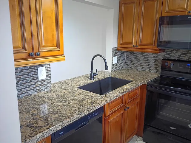a kitchen with granite countertop a sink and a stove
