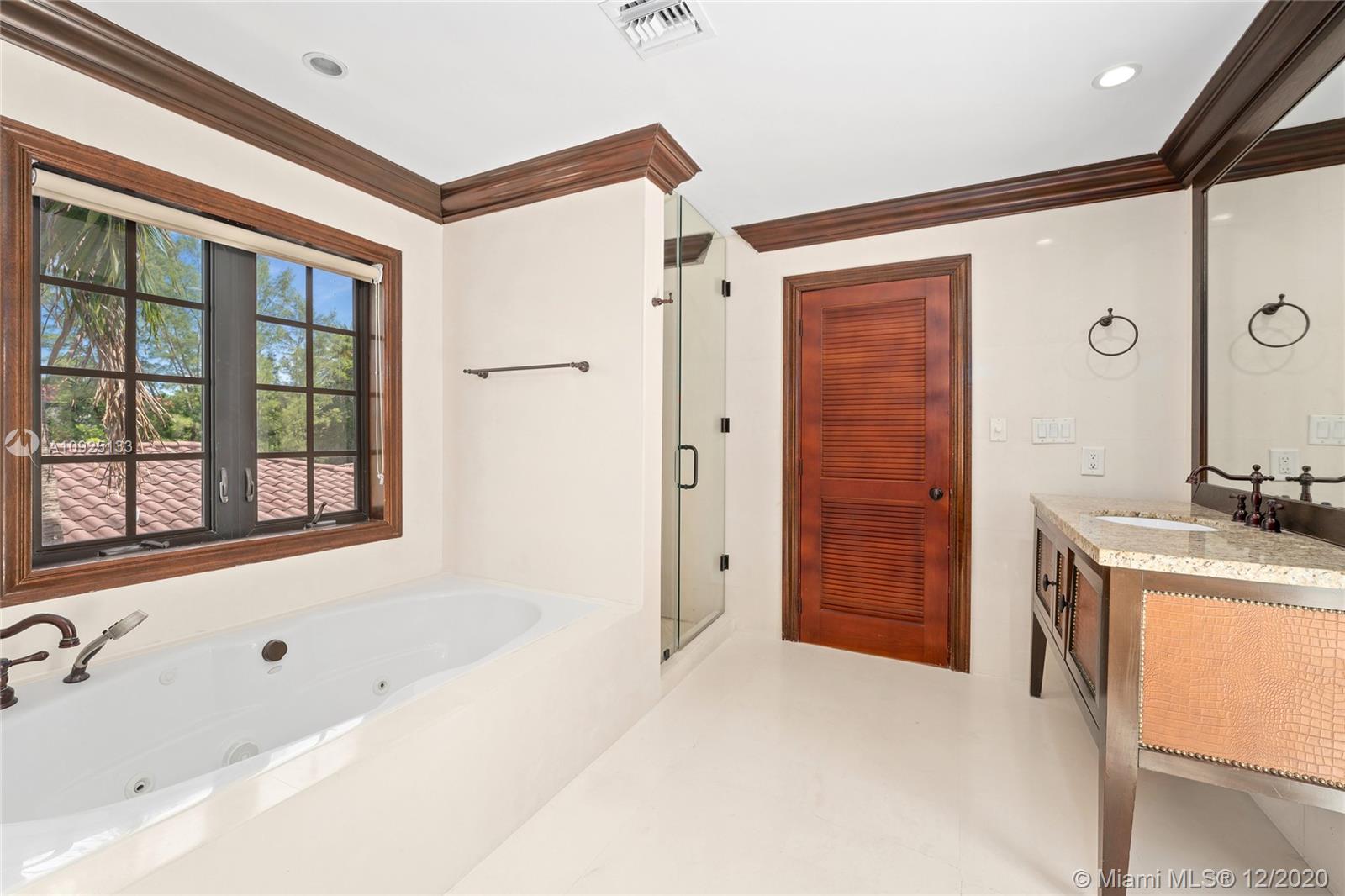 5300 Pine Tree Drive Miami Beach, FL 33140 - Photo 25 of 40 a bathroom with a tub a sink and a large mirror