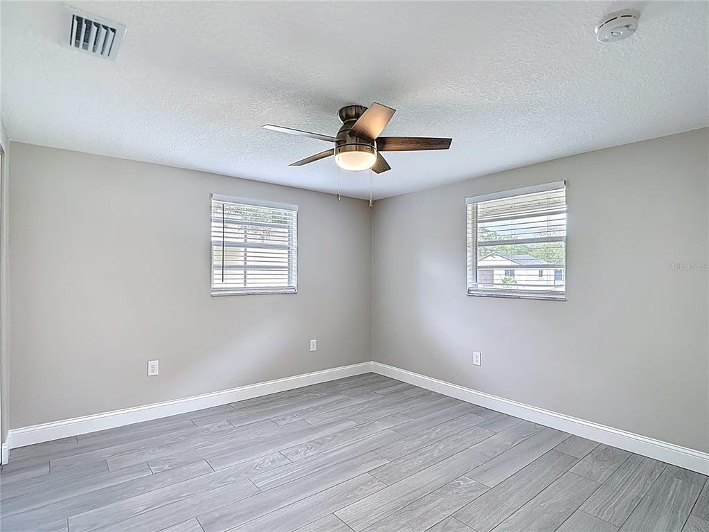 14306 Guava Street Hudson, FL 34667 - Photo 11 of 39 a view of empty room with wooden floor and fan