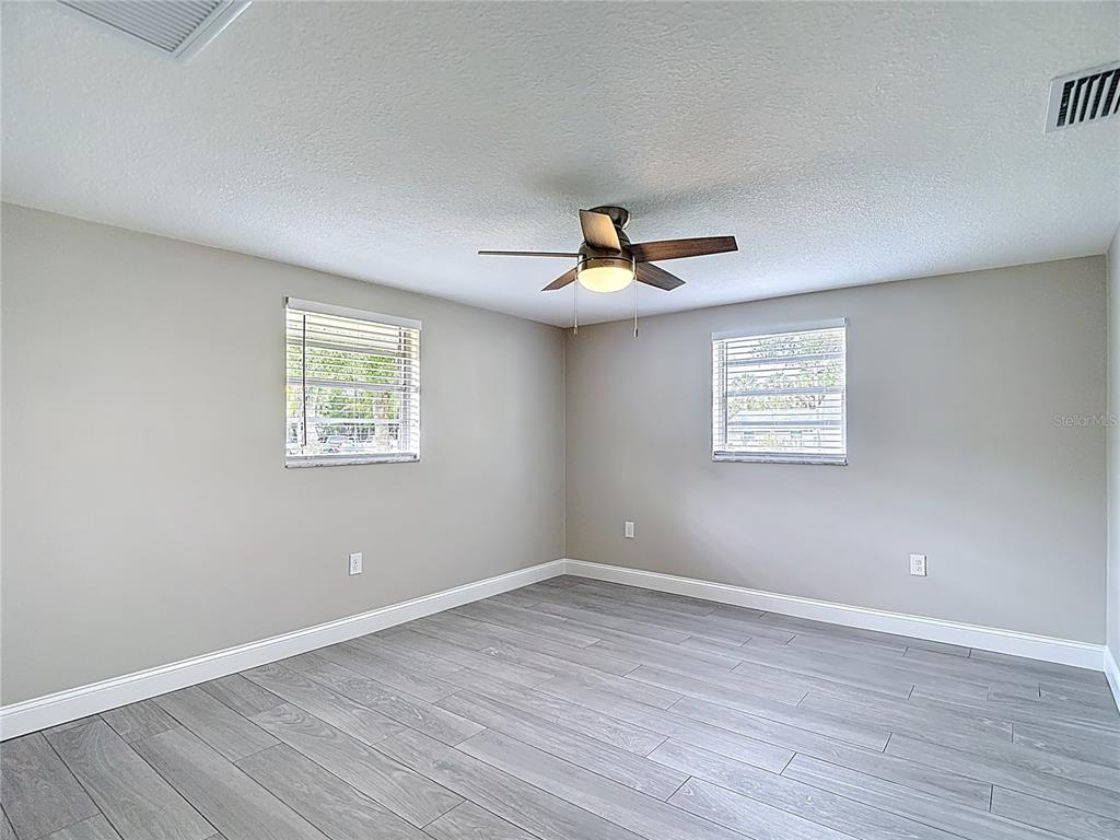 14306 Guava Street Hudson, FL 34667 - Photo 15 of 39 a view of an empty room with a window and wooden floor