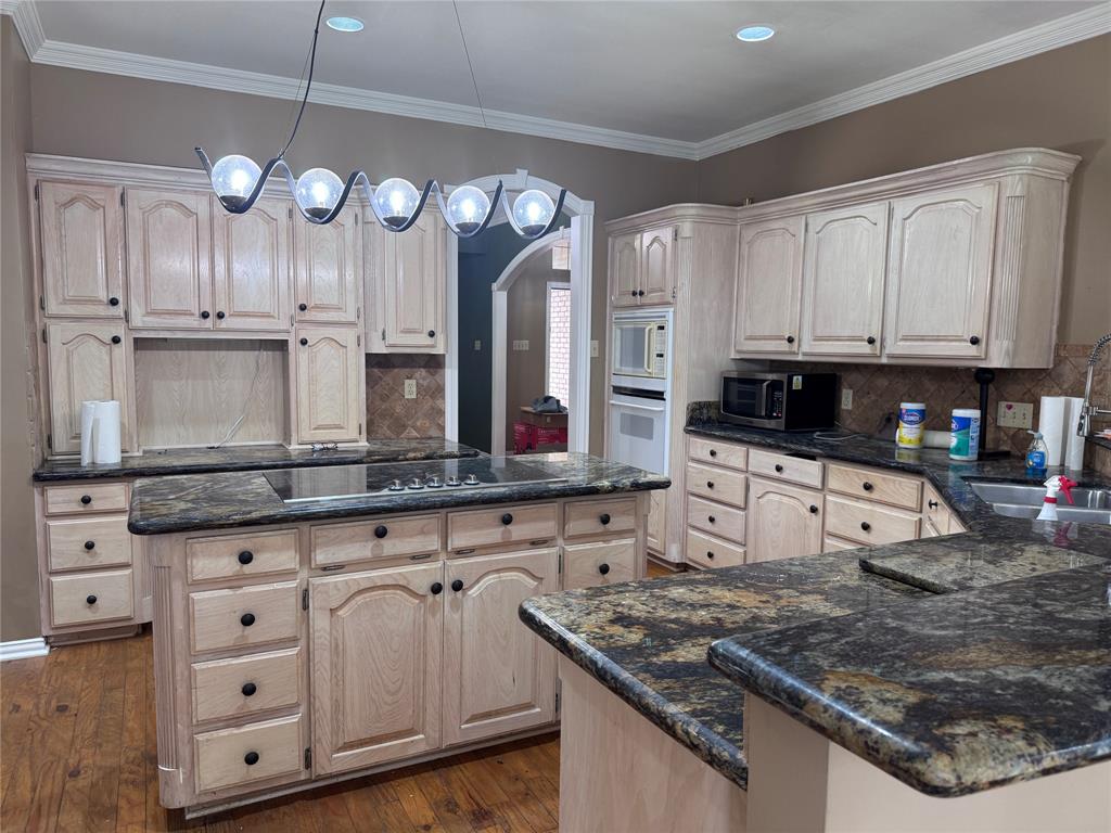 1704 South Bowen Road Pantego, TX 76013 - Photo 11 of 37 Kitchen featuring extensive light wood cabinetry, granite countertops, a built-in oven, and a cooktop on the center island with storage!