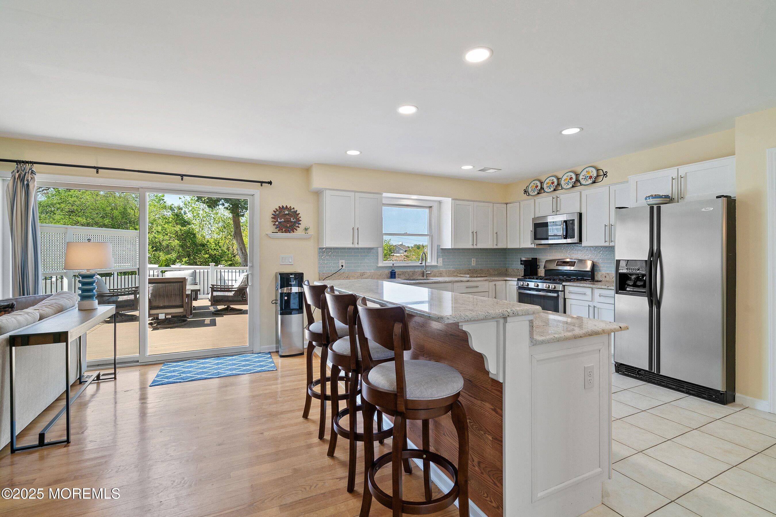 39 Ivy Court Bayville, NJ 08721 - Photo 5 of 33 a kitchen with stainless steel appliances granite countertop a refrigerator a microwave oven a stove and a dining table with wooden floor