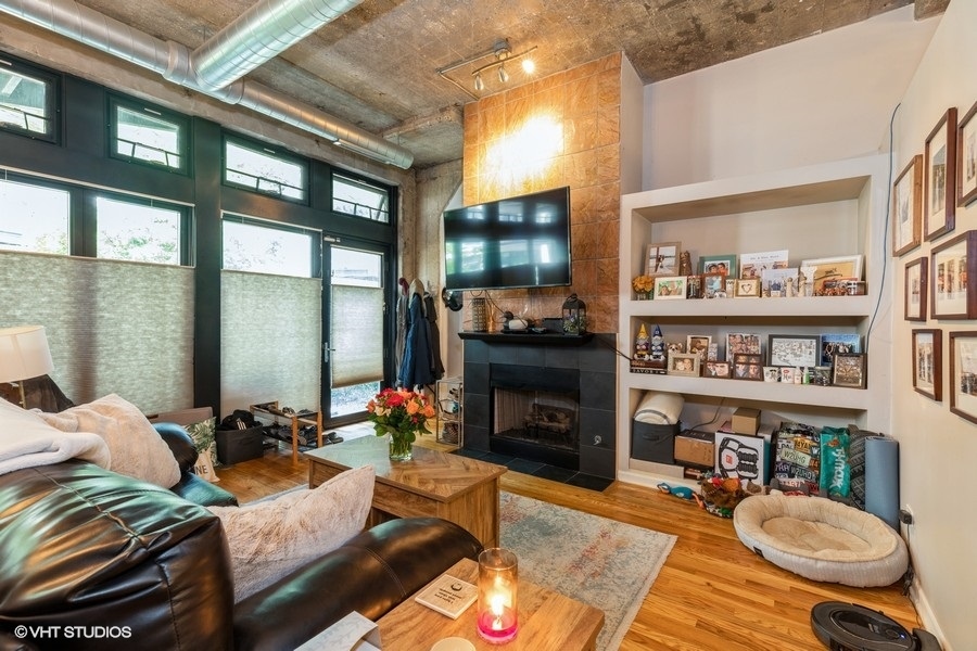 1070 West 15th Street, Unit 102 Chicago, IL 60608 - Photo 8 of 20 a living room with furniture a bookshelf and a fireplace