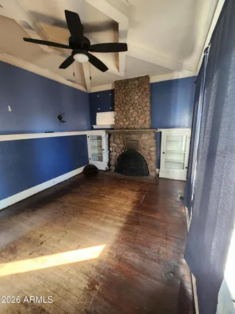 a view of an empty room with wooden floor and a fireplace