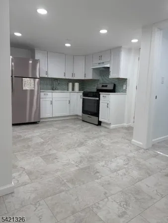 a kitchen with granite countertop a refrigerator and white cabinets