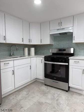 a kitchen with granite countertop white cabinets and stainless steel appliances