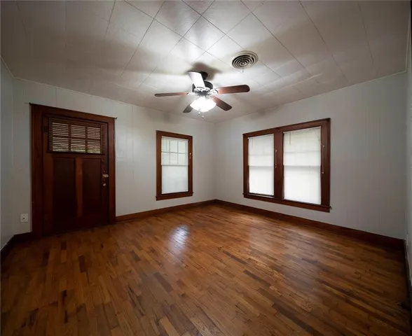 a view of an empty room with a window and wooden floor