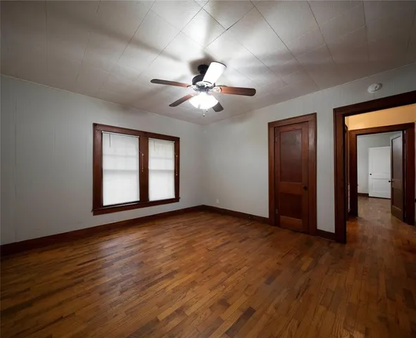 a view of an empty room with window and wooden floor
