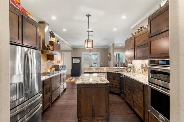 a modern kitchen with stainless steel appliances granite countertop a stove refrigerator and a sink