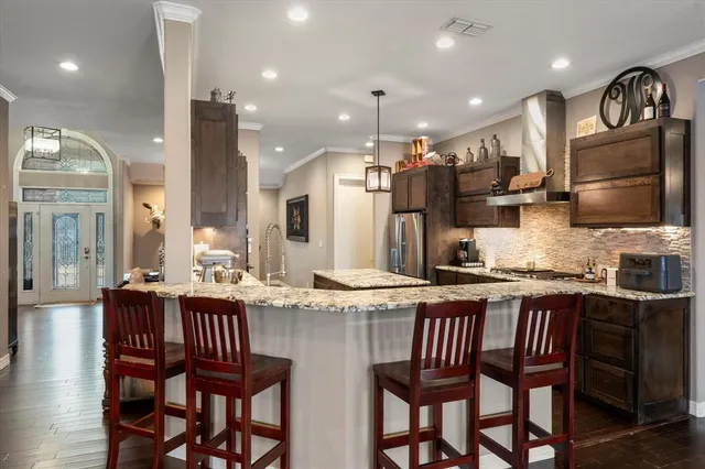 a kitchen with granite countertop a dining table chairs cabinets and stainless steel appliances