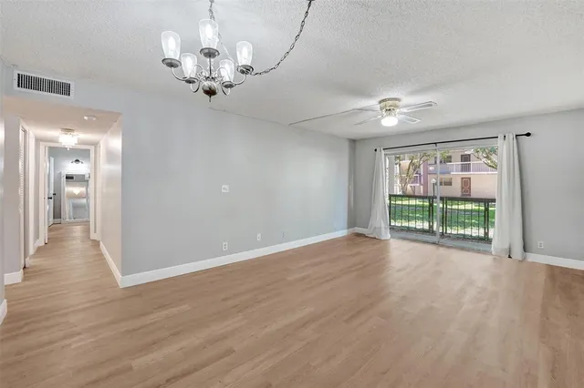 a view of a livingroom with a chandelier fan and windows