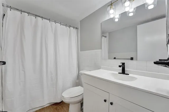 a bathroom with a sink a toilet a mirror and shower curtain