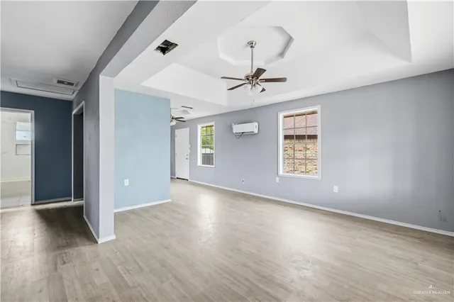a view of an empty room with a window and wooden floor