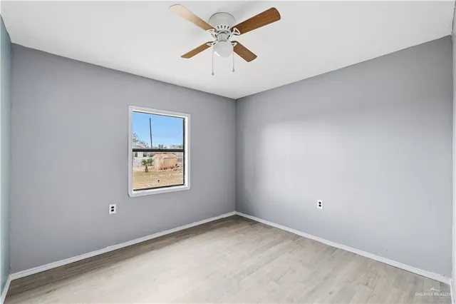 an empty room with a window and a ceiling fan
