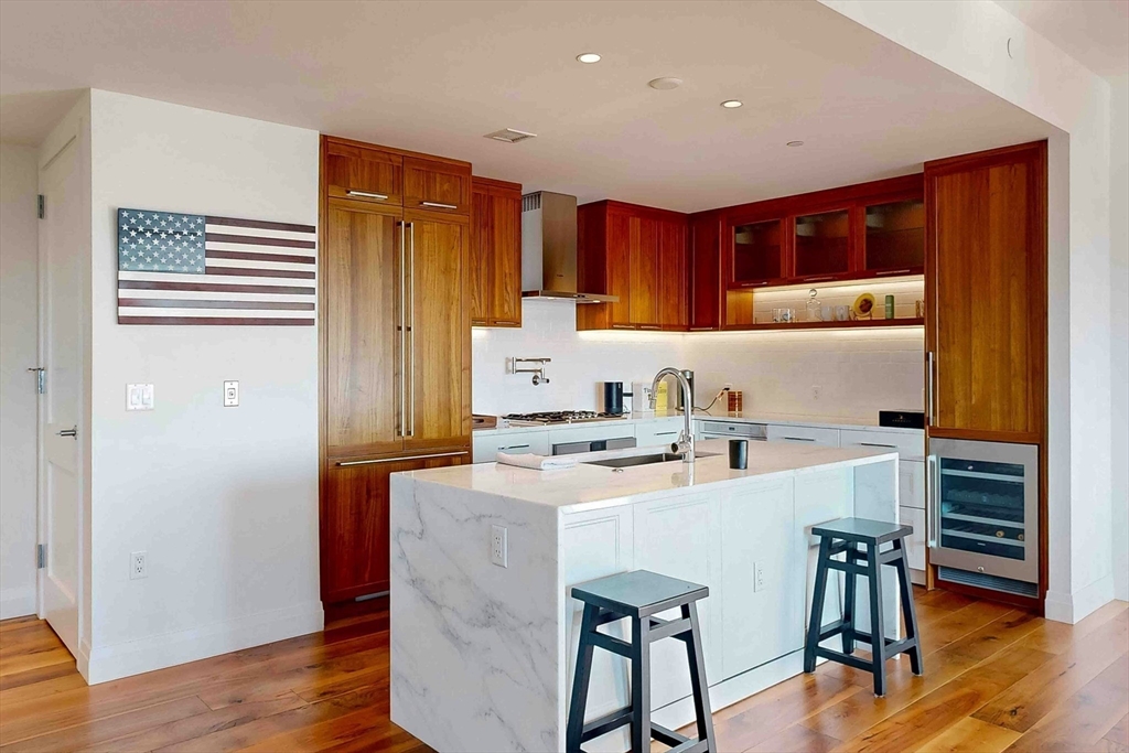 300 Pier 4 Blvd., Unit 6E Boston, MA 02210 - Photo 16 of 36 a kitchen with a sink a stove cabinets and wooden floor