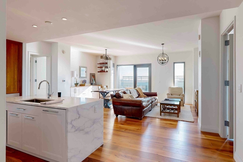 300 Pier 4 Blvd., Unit 6E Boston, MA 02210 - Photo 2 of 36 a living room with kitchen view and hardwood floor