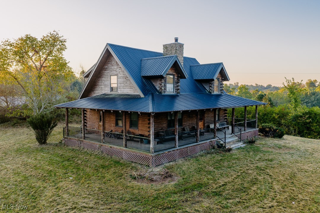 5991 Sandy Ridge Road Southeast Tippecanoe, OH 44699 - Photo 1 of 34 Front of house with log siding, a chimney, a porch, a metal roof, and a lawn