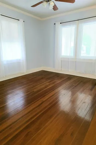 a view of an empty room with wooden floor and a window