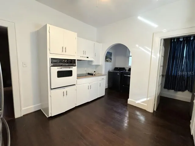a kitchen with a white cabinets and wooden floor